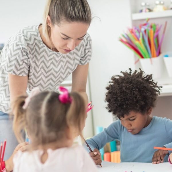 Nursery school teacher surrounded by young children at a table