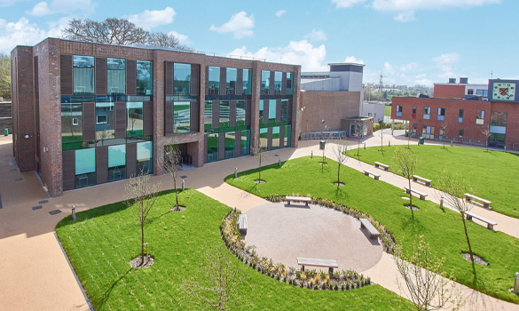 Modern school building with lots of windows overlooking a grass quad