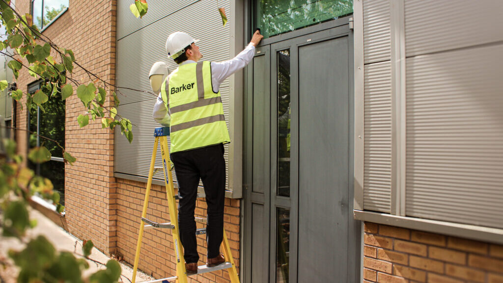 A surveyor in Barker PPE inspecting an external door